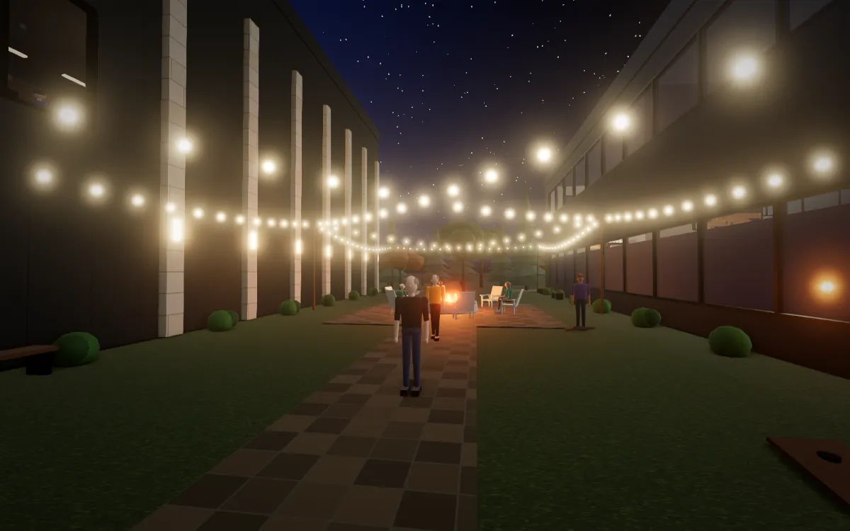 The courtyard lawn at night under string lights, with a fire pit between the two buildings